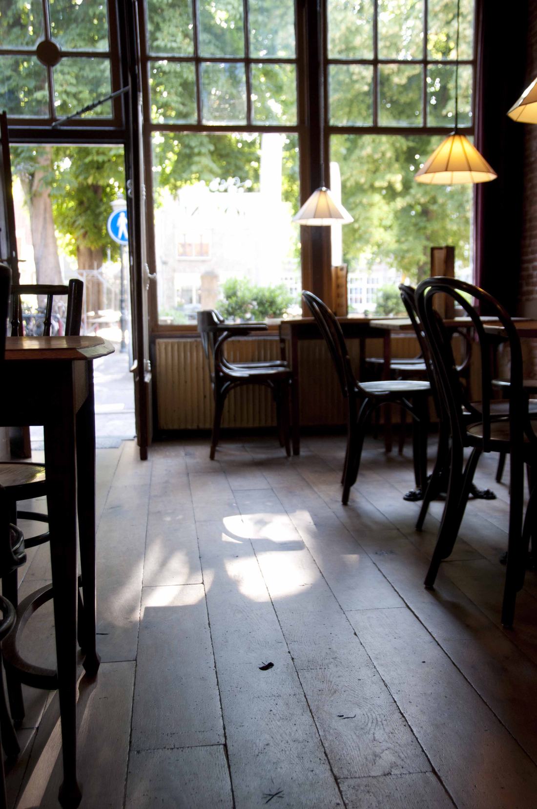 Interieur van Sint John: bentwood-stoelen en houten vloer in het licht van de ramen aan de Vismarkt
